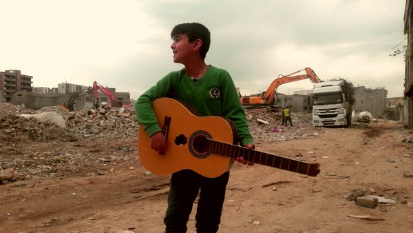 Aylar süre ablukadan sonra Suriye'ye dönmüş Cizre'de, evlerinin enkazından kurtardığı kırık gitarıyla "Li Qamişlo" şarkısını söyleyen çocuktur umut.